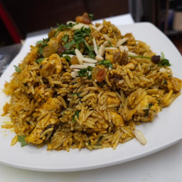 Chicken Biryani from Akbar Cuisine of India, topped with raisins, slivered almonds, and fresh cilantro.