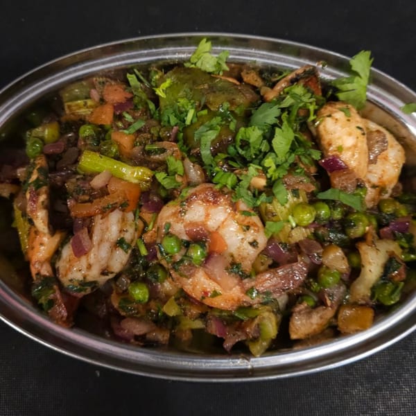 Indian shrimp dish with green peas, red onions, and cilantro in a silver bowl.
